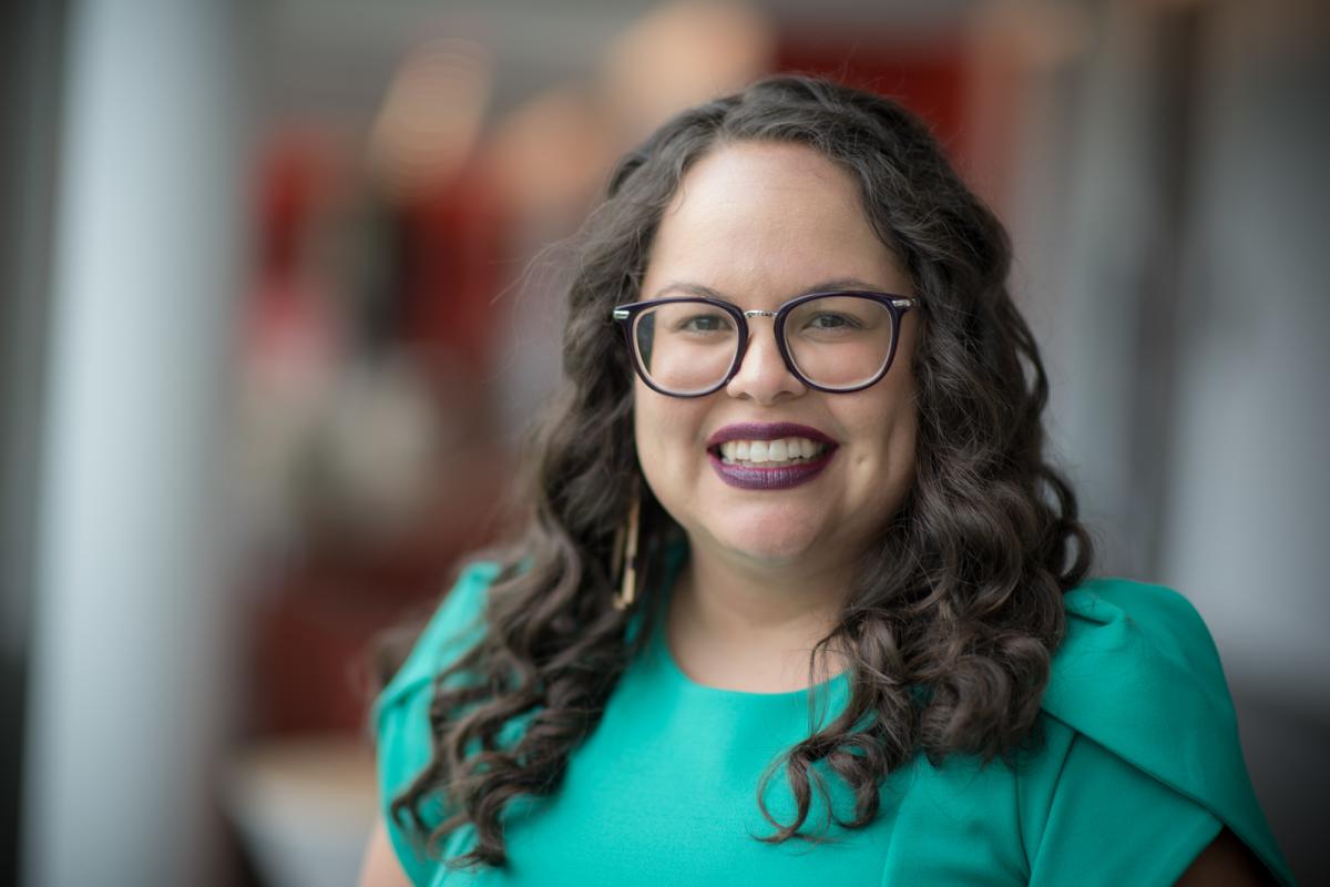 MPA student smiling, wearing a blue shirt and glasses, in a campus setting.