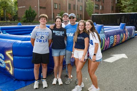 Family stands in front of inflatable game wearing Westfield State tshirts
