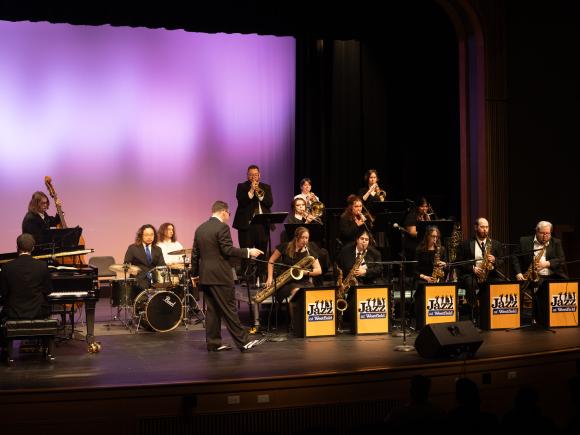 Westfield State University jazz musicians performing on stage with saxophones, trumpets, and drums.