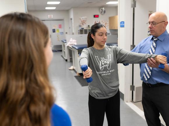 Faculty member guiding a student through a hands-on activity in an athletic training class.