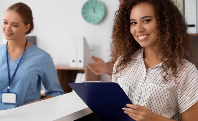 Medical Administrative Assistant smiling with a clip board.