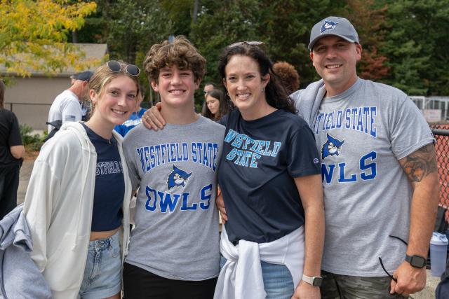 A family smiling together during Family Weekend at Westfield State University, wearing WSU shirts.