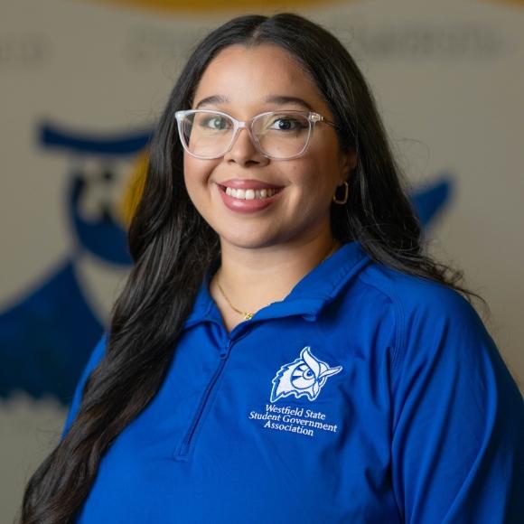 SGA Vice President of Belonging, Lorraine wearing a blue shirt smiling.
