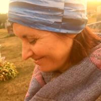 Woman looks down with sun behind her